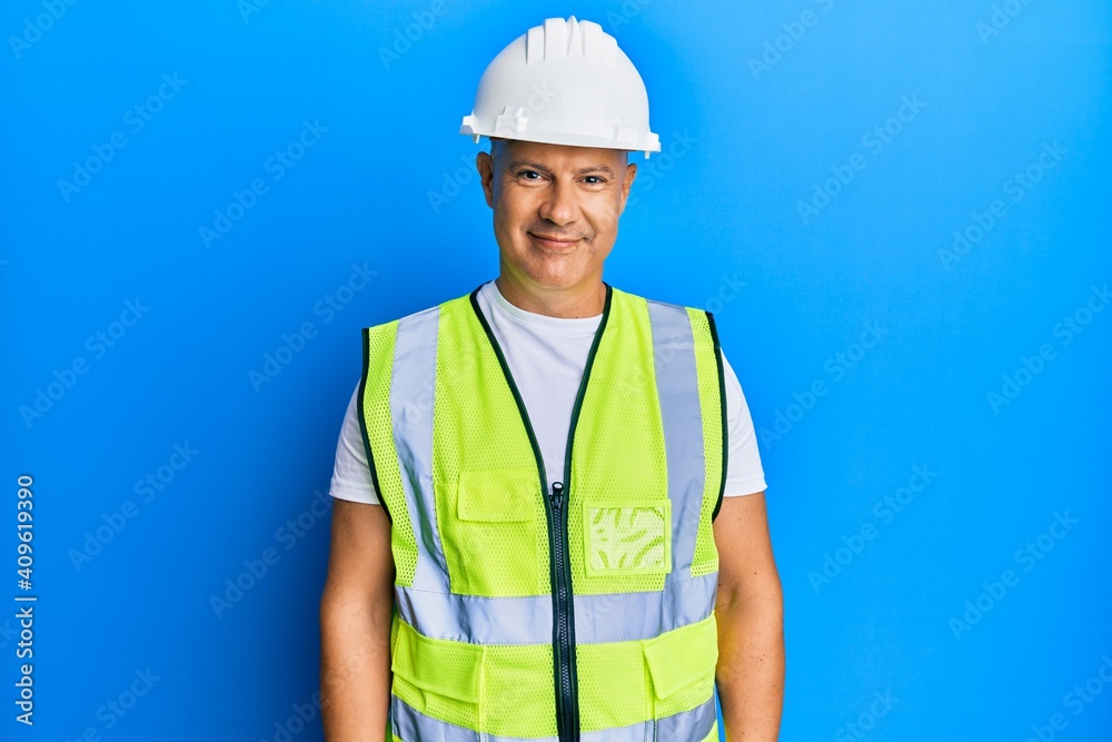 Middle age bald man wearing architect hardhat with a happy and cool smile on face. lucky person. Middle age bald man wearing architect hardhat with a happy and cool smile on face. lucky person.