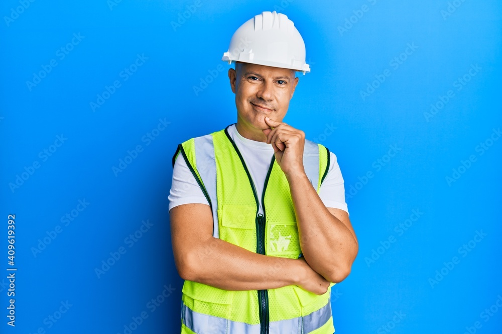 Middle age bald man wearing architect hardhat smiling looking confident at the camera with crossed arms and hand on chin. thinking positive. Middle age bald man wearing architect hardhat smiling looking confident at the camera with crossed arms and hand on chin. thinking positive.