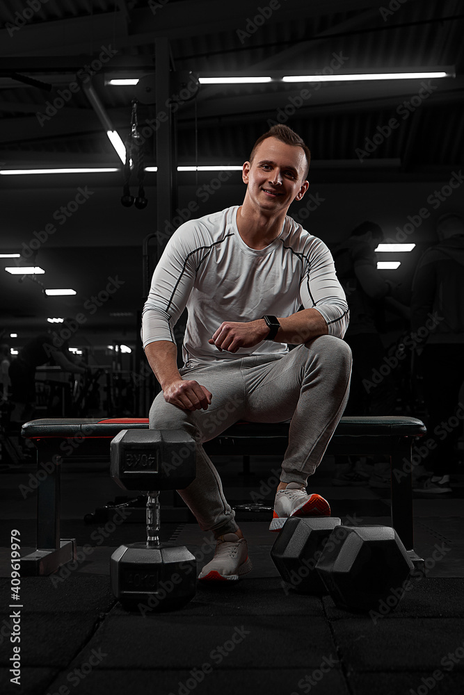 Handsome man with big muscles, posing at the camera in the gym. model in white sportswear Handsome man with big muscles, posing at the camera in the gym. model in white sportswear