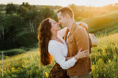 Beautiful young woman and a man walk, hug and kiss in nature at sunset.