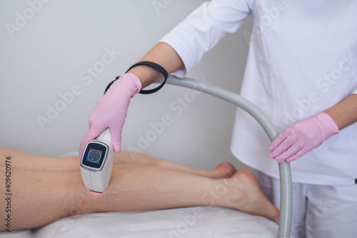 Laser epilation and cosmetology in beauty salon. Hair removal procedure. Laser epilation  cosmetology  spa  and hair removal concept. Beautiful blonde woman getting hair removing on legs.