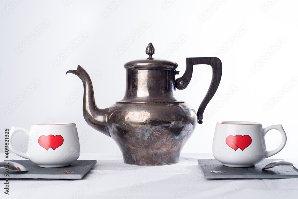 Teapot and two cups with hearts painted on them. Romantic tea time or breakfast. Concept of love and Valentines day Teapot and two cups with hearts painted on them. Romantic tea time or breakfast. Concept of love and Valentines day