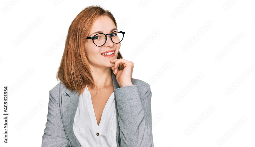 Young caucasian woman wearing business style and glasses looking confident at the camera smiling with crossed arms and hand raised on chin. thinking positive.