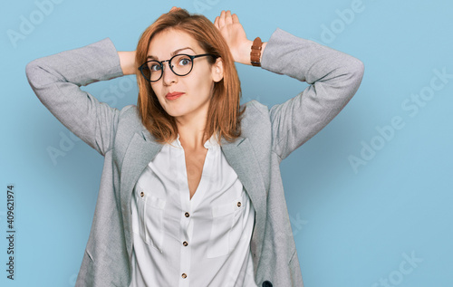 Young caucasian woman wearing business style and glasses doing bunny ears gesture with hands palms looking cynical and skeptical. easter rabbit concept. photo