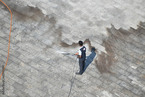 man cleaning floor with high pressure water jet spray