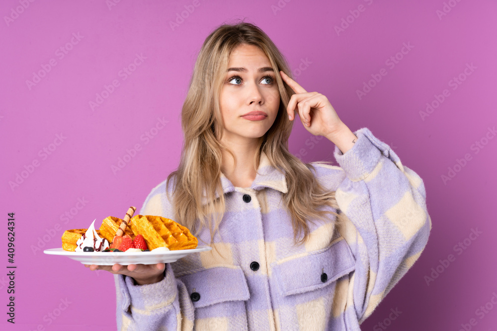 Teenager Russian girl holding waffles isolated on purple background having doubts and thinking Teenager Russian girl holding waffles isolated on purple background having doubts and thinking