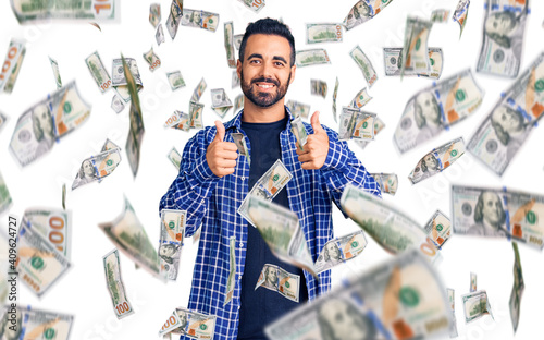 Young hispanic man wearing casual clothes success sign doing positive gesture with hand, thumbs up smiling and happy. cheerful expression and winner gesture. photo