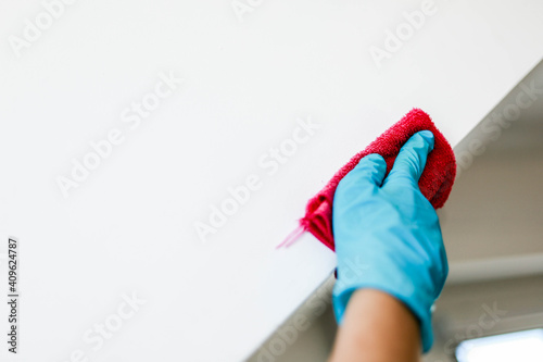 A male employee is wiping the edges of the walls in a restaurant, cleaning to prevent the transmission of COVID-19, COVID-19 prevention concept.