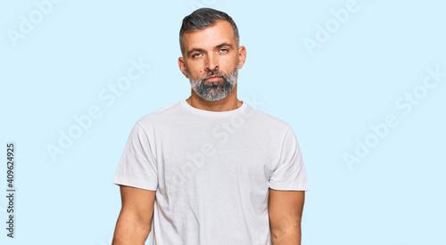 Middle age handsome man wearing casual white tshirt looking sleepy and tired, exhausted for fatigue and hangover, lazy eyes in the morning.