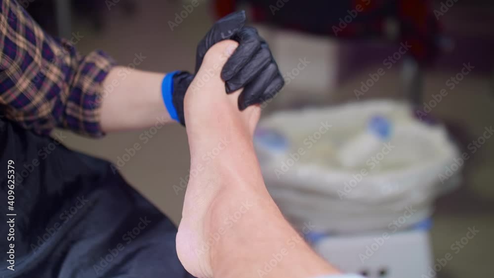 Manicurist in black gloves applies cream on toes after pedicure. Close up view. Manicurist in black gloves applies cream on toes after pedicure. Close up view.