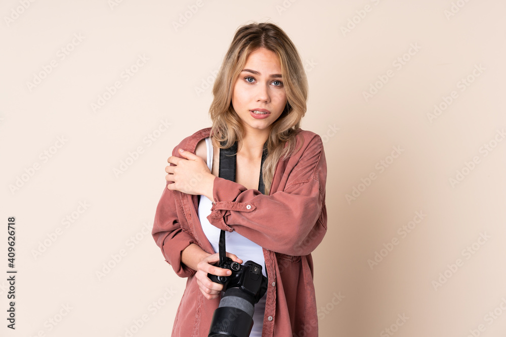 Young photographer girl over isolated background freezing Young photographer girl over isolated background freezing