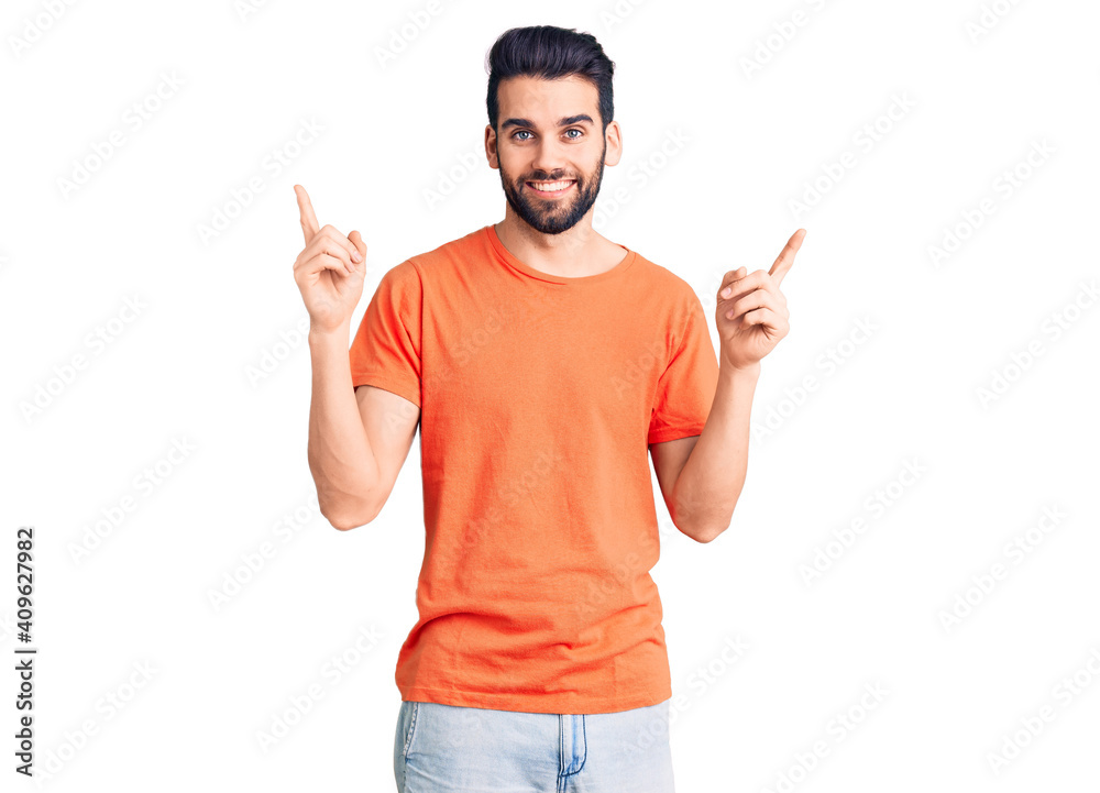 Young handsome man with beard wearing casual t-shirt smiling confident pointing with fingers to different directions. copy space for advertisement Young handsome man with beard wearing casual t-shirt smiling confident pointing with fingers to different directions. copy space for advertisement