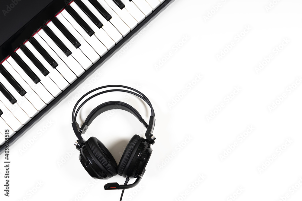Music background. Black digital piano and headphones with microphone on white background. Top view