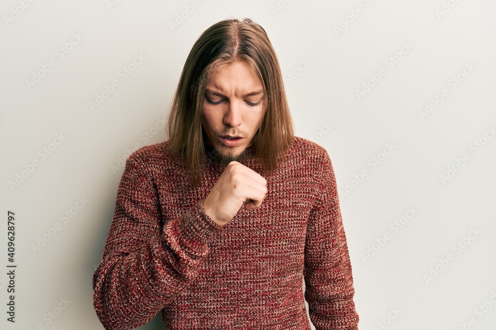 Handsome caucasian man with long hair wearing casual winter sweater feeling unwell and coughing as symptom for cold or bronchitis. health care concept. Handsome caucasian man with long hair wearing casual winter sweater feeling unwell and coughing as symptom for cold or bronchitis. health care concept.