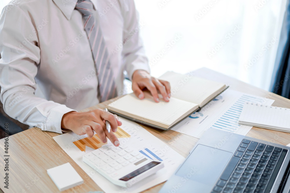 A business man uses a calculator to check monthly sales of a salesperson from a sales summary document in a bar graph format. Sales management concept. A business man uses a calculator to check monthly sales of a salesperson from a sales summary document in a bar graph format. Sales management concept.
