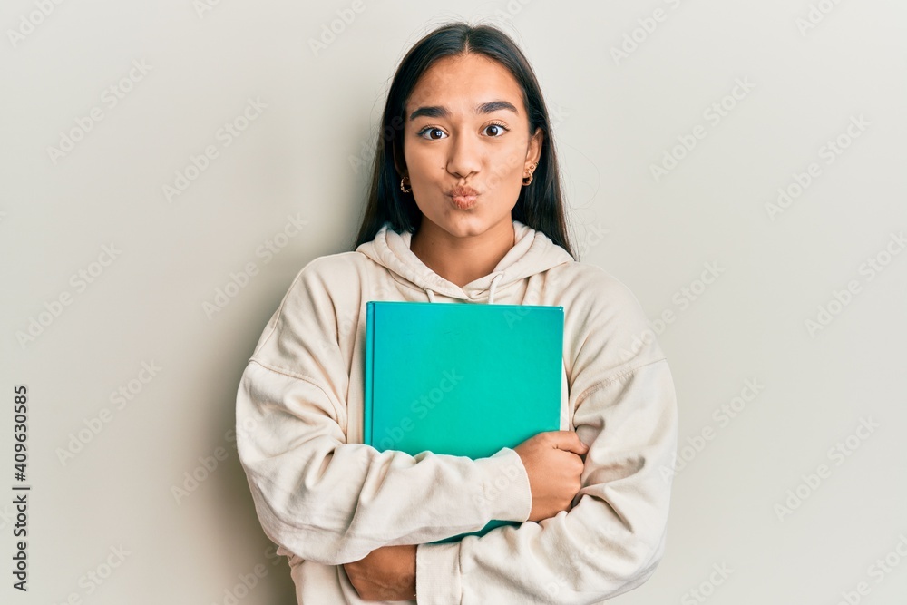 Young asian woman holding book looking at the camera blowing a kiss being lovely and sexy. love expression. Young asian woman holding book looking at the camera blowing a kiss being lovely and sexy. love expression.