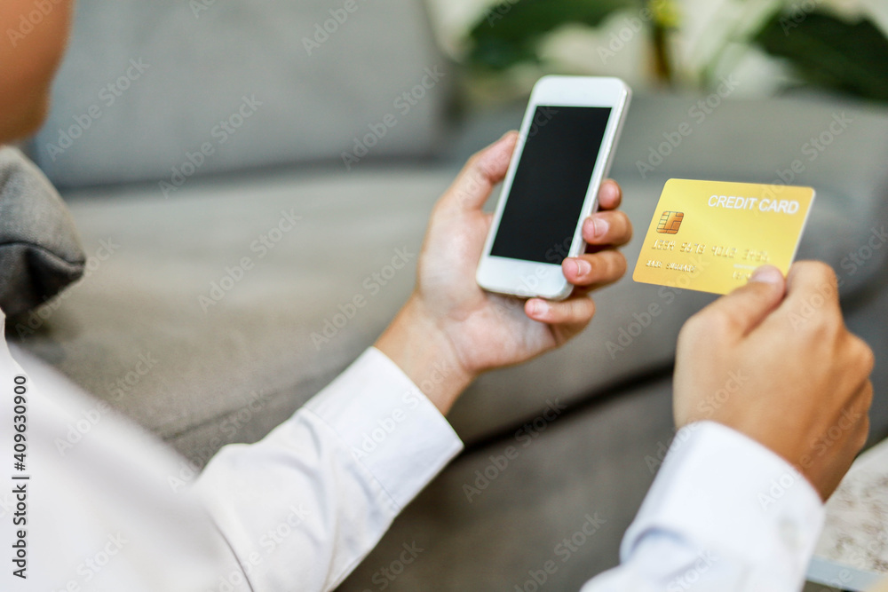 Man holding a moblie phone and a gold credit card, he is filling out credit card information on his phone to work, pay bills online, online shopping ideas. Man holding a moblie phone and a gold credit card, he is filling out credit card information on his phone to work, pay bills online, online shopping ideas.