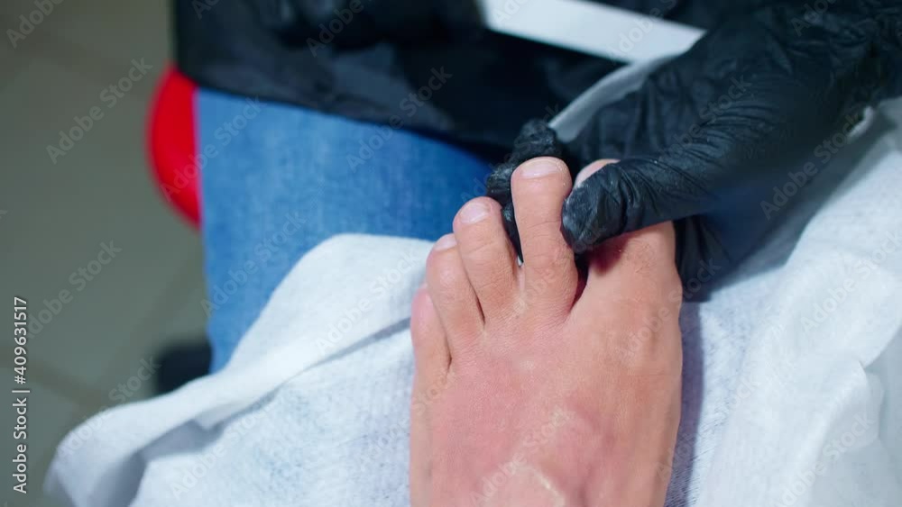 Vidéo Stock Manicurist cuts dry skin on man's toes using metal nippers