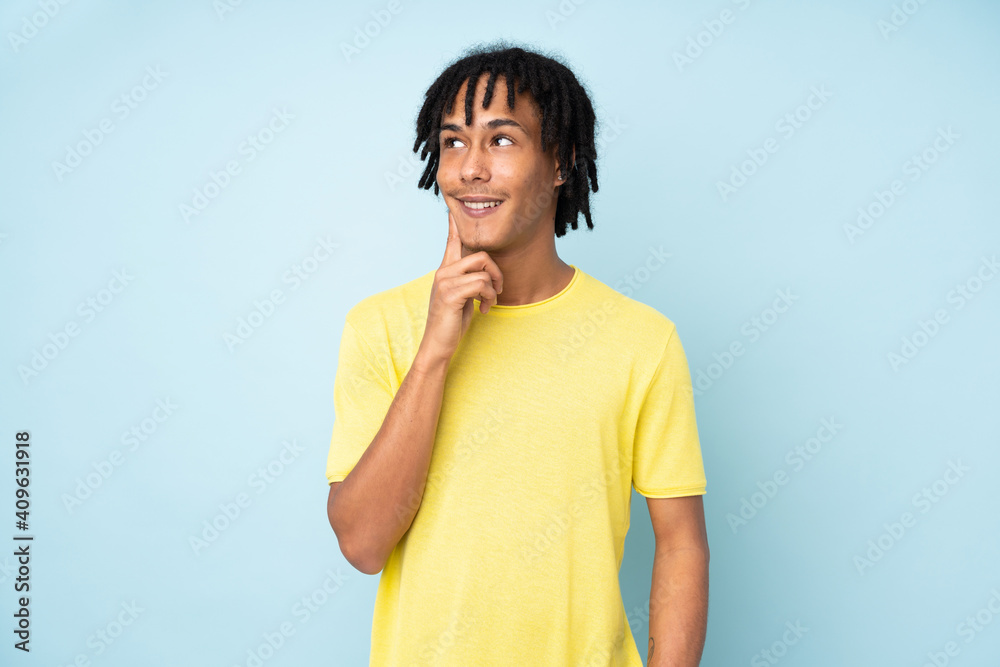 Young african american man isolated on blue background thinking an idea while looking up Young african american man isolated on blue background thinking an idea while looking up