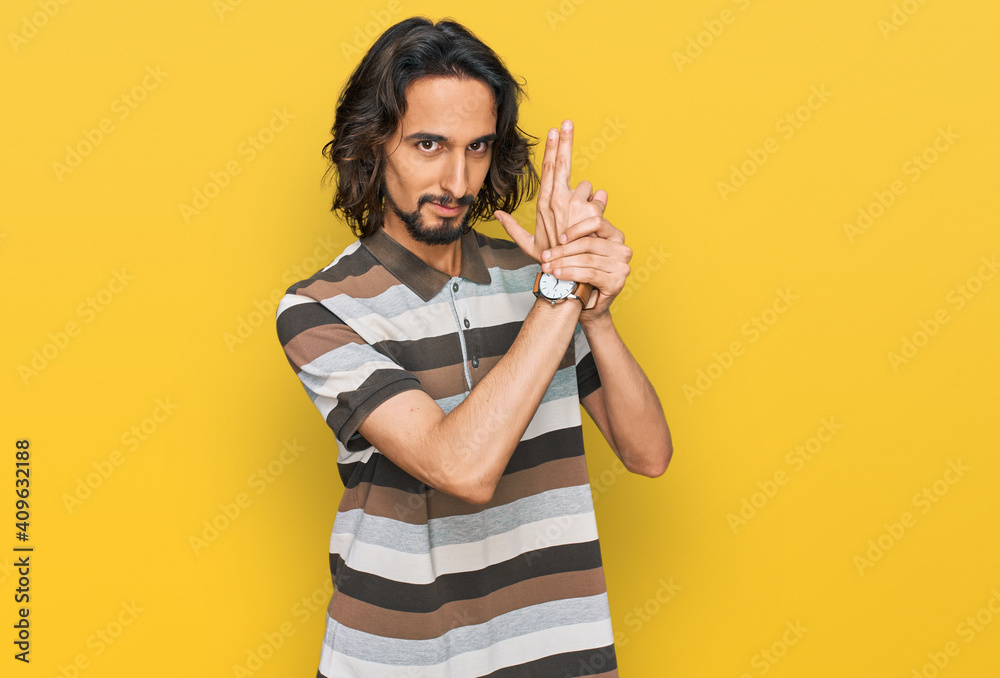 Young hispanic man wearing casual clothes holding symbolic gun with hand gesture, playing killing shooting weapons, angry face Young hispanic man wearing casual clothes holding symbolic gun with hand gesture, playing killing shooting weapons, angry face