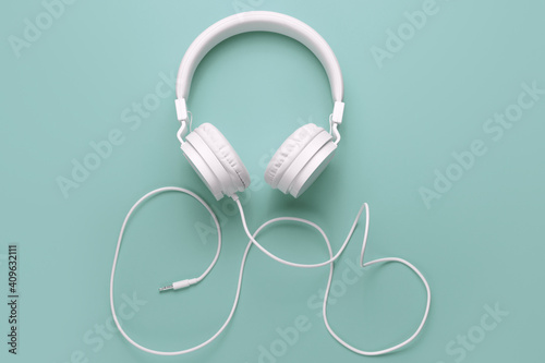Modern white headphone on cyan background. Music concept.