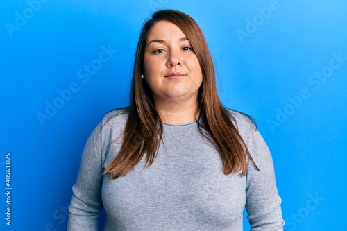 Beautiful brunette plus size woman wearing casual clothes relaxed with serious expression on face. simple and natural looking at the camera.