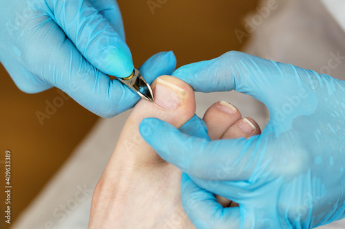 Master chiropody removes the cuticle. Cuticle treatment is one of the stages of processing the cuticle. Woman legs at pedicure procedures. Spa. Concept body care. Clinic Podiatry Podology.