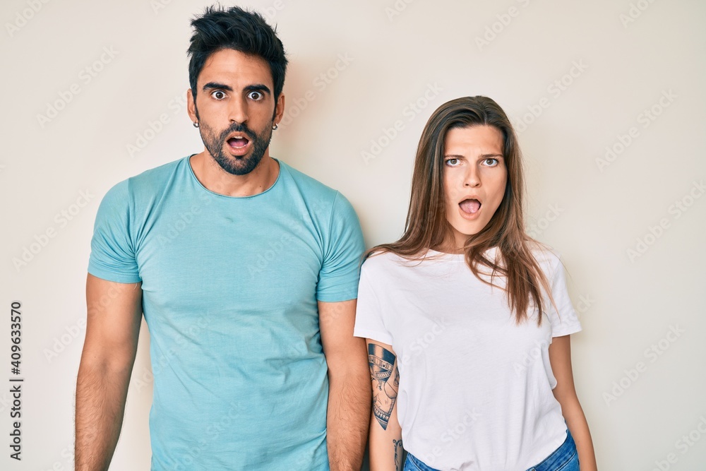 Beautiful young couple of boyfriend and girlfriend together in shock face, looking skeptical and sarcastic, surprised with open mouth Beautiful young couple of boyfriend and girlfriend together in shock face, looking skeptical and sarcastic, surprised with open mouth