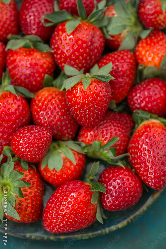 Ripe strawberries in a plate close-up on a blue-green background Ripe strawberries in a plate close-up on a blue-green background