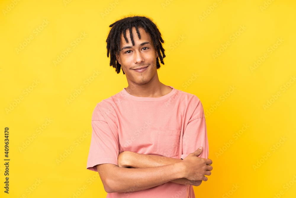 Young african american man isolated on yellow background keeping the arms crossed in frontal position Young african american man isolated on yellow background keeping the arms crossed in frontal position