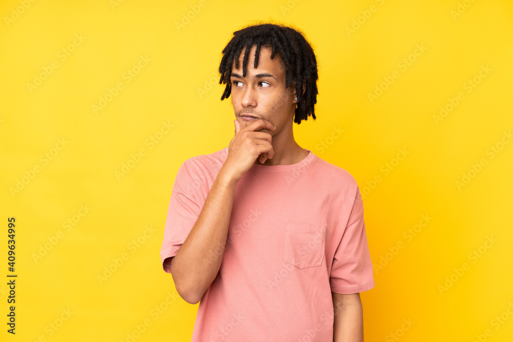 Young african american man isolated on yellow background having doubts and with confuse face expression