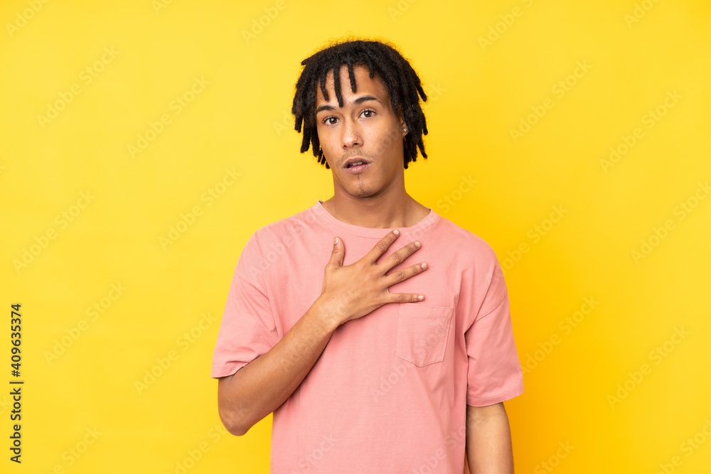 Young african american man isolated on yellow background surprised and shocked while looking right Young african american man isolated on yellow background surprised and shocked while looking right