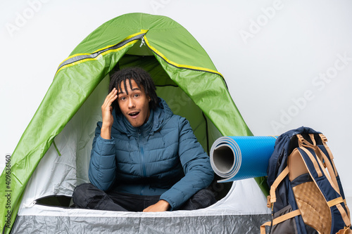 Young african american man inside a camping green tent has just realized something and has intending the solution