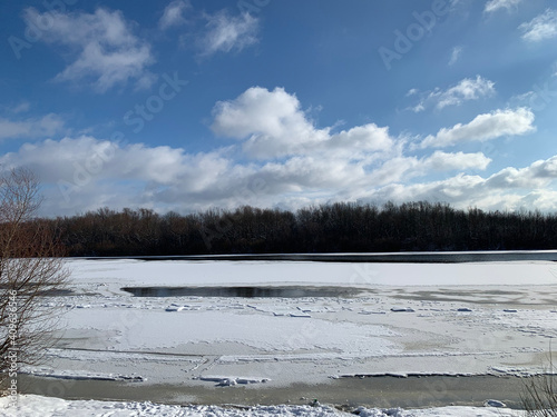 Winter forest on the river at sunset. Colorful landscape with snowy trees, beautiful frozen river with reflection in water. Seasonal. Winter trees, lake and blue sky. Frosty snowy river