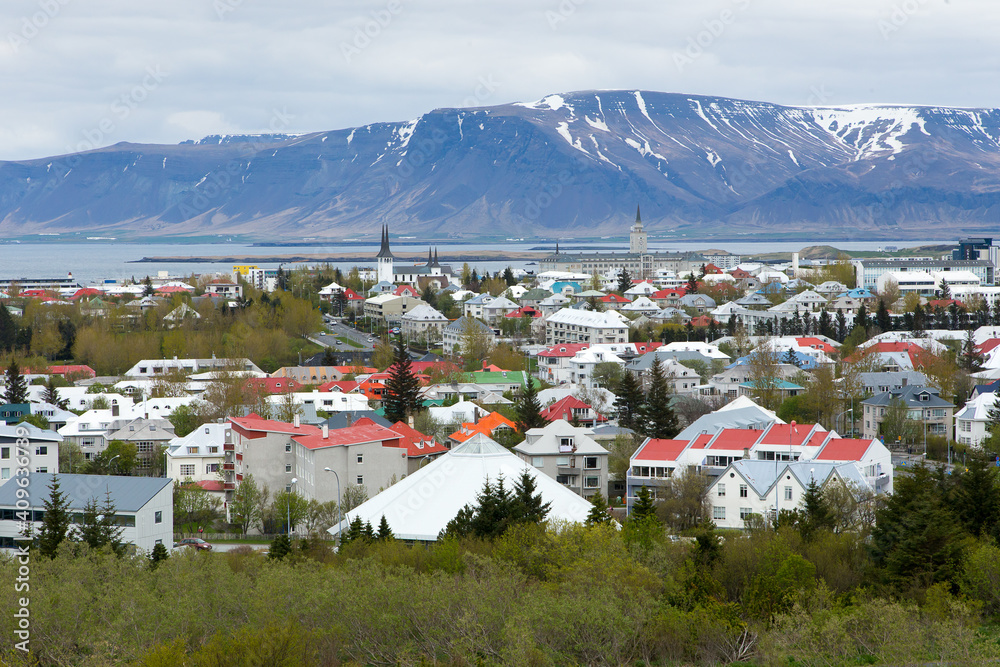 Fototapeta premium Aerial view of downtown rooftops seen during a grey cloudy day, with sea and mountains in the background, Reykjavik, Iceland