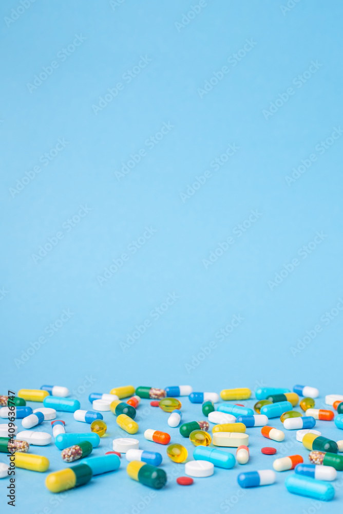 Vertical photo of many different pills and capsules on blue background. Photo with free empty space above colorful pills Vertical photo of many different pills and capsules on blue background. Photo with free empty space above colorful pills