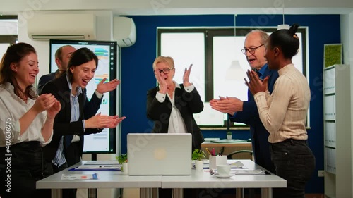 Motivated happy diverse business team people clapping celebrating success at corporate meeting. Multiethnical designers giving high five during corporate brainstorm receving good news enjoying victory photo