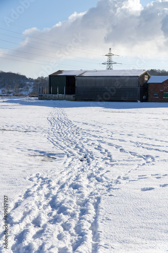 Tracks in snow leading to a farm barn