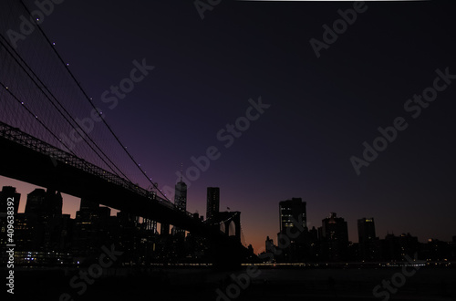 Brooklyn bridge and lower manhattan at night after sunset with colorful skies