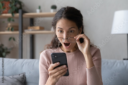 Head shot emotional young woman looking at smartphone screen with opened mouth, feeling surprised with received offer. Amazed millennial lady getting sms with unbelievable news. shocked by sale prices