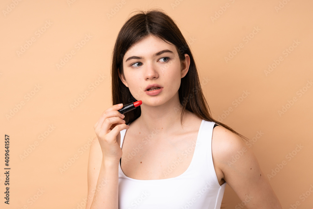 Young Ukrainian teenager girl over isolated background holding red lipstick Young Ukrainian teenager girl over isolated background holding red lipstick