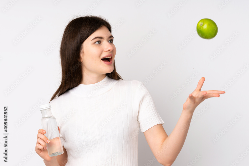 Young Ukrainian teenager girl over isolated white background with an apple and with a bottle of water Young Ukrainian teenager girl over isolated white background with an apple and with a bottle of water