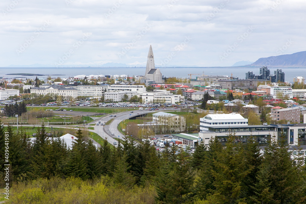 
Aerial view of downtown buildings dominated by the famous 1986 Hallgrimskirkja church seen during a grey cloudy day, with sea and mountains in the background, Reykjavik, Iceland