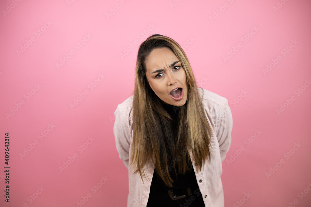 Young beautiful blonde woman with long hair standing over pink background afraid and shocked with surprise and amazed expression, fear and excited face. Young beautiful blonde woman with long hair standing over pink background afraid and shocked with surprise and amazed expression, fear and excited face.