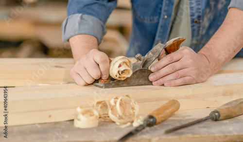 Close up carpenter's hands planed wood in a workshop