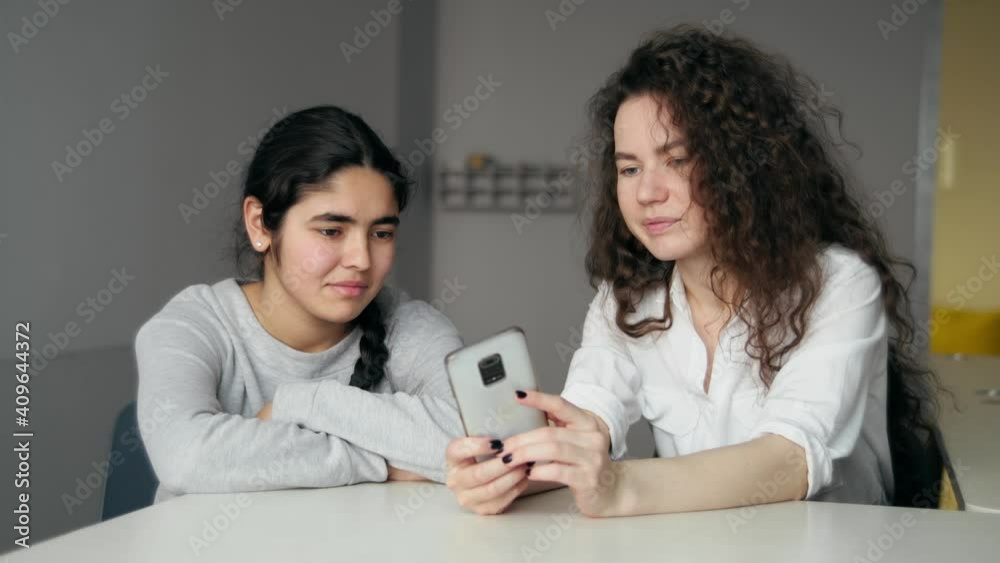 two girls of different ages and races are looking at the screen of a mobile phone. two girls of different ages and races are looking at the screen of a mobile phone.