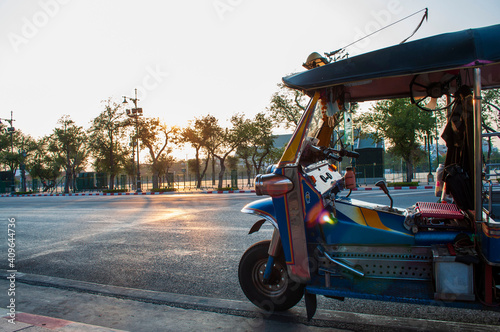 Thai tuk-tuks land on the road at sunset.