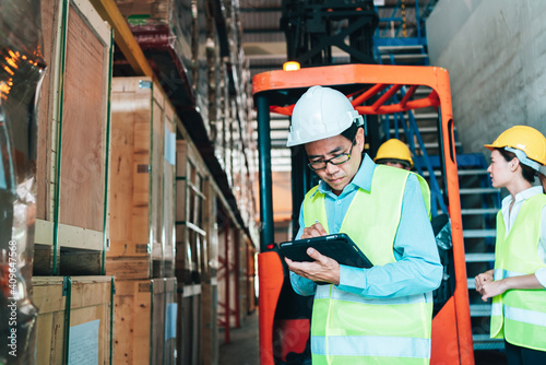 Working Team at warehouse. asian man Engineer use Tablet Information to further placement in storage department. background driver at Warehouse forklift loader works with goods