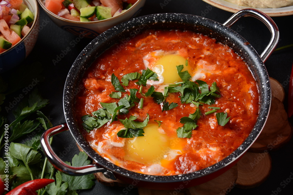 Shakshouka, eggs poached in sauce of tomatoes, olive oil, peppers, onion and garlic, Mediterranean cuisine Shakshouka, eggs poached in sauce of tomatoes, olive oil, peppers, onion and garlic, Mediterranean cuisine