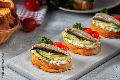 Smoked sprat sandwich - fish, fresh cucumber and tomato. Sprat sandwiches on toasted slices of bread